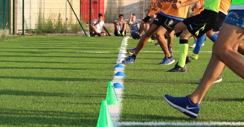 A group of people running together on a grass field towards a white painted line