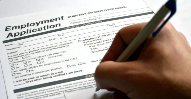 A hand holding a pen completing an application form