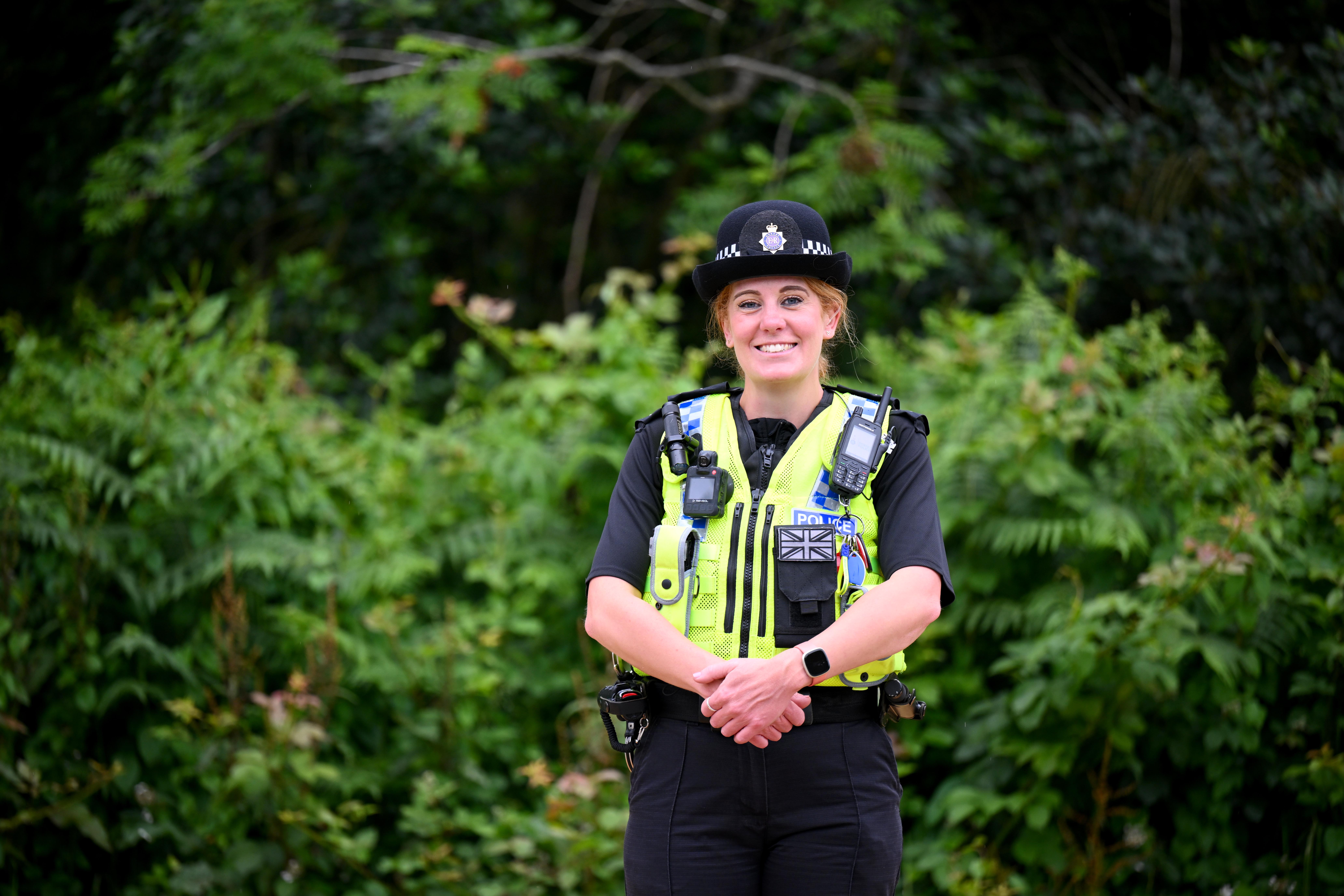 A female Special Constable smiling with trees in the background