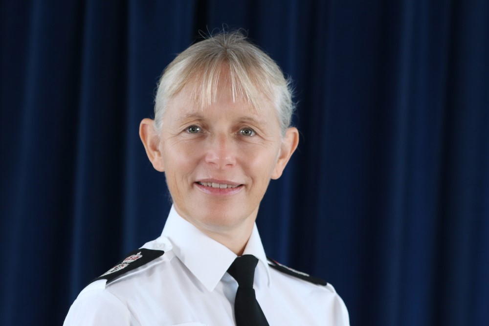 Officer standing looking at a coastal town from a coast path at sunset