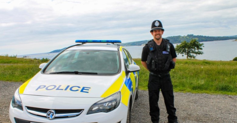 An officers stood next to his patrol car