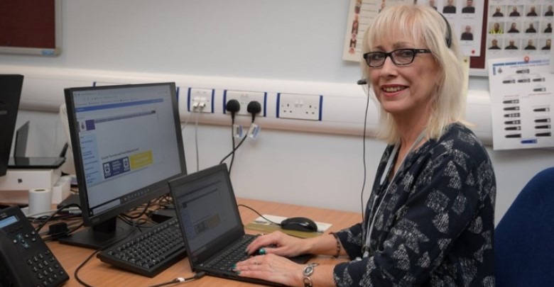 Smiling female police staff member sat at desk