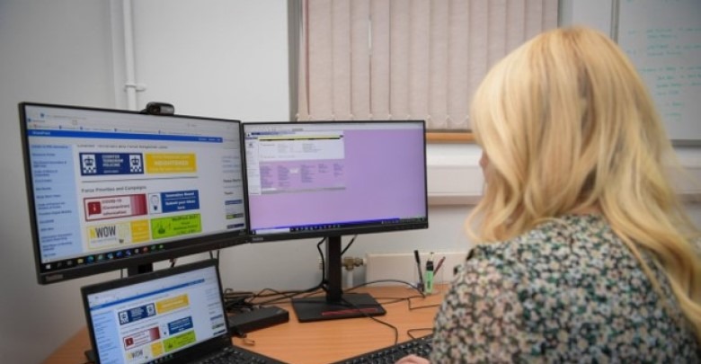Person sat at a desk in front of three screens