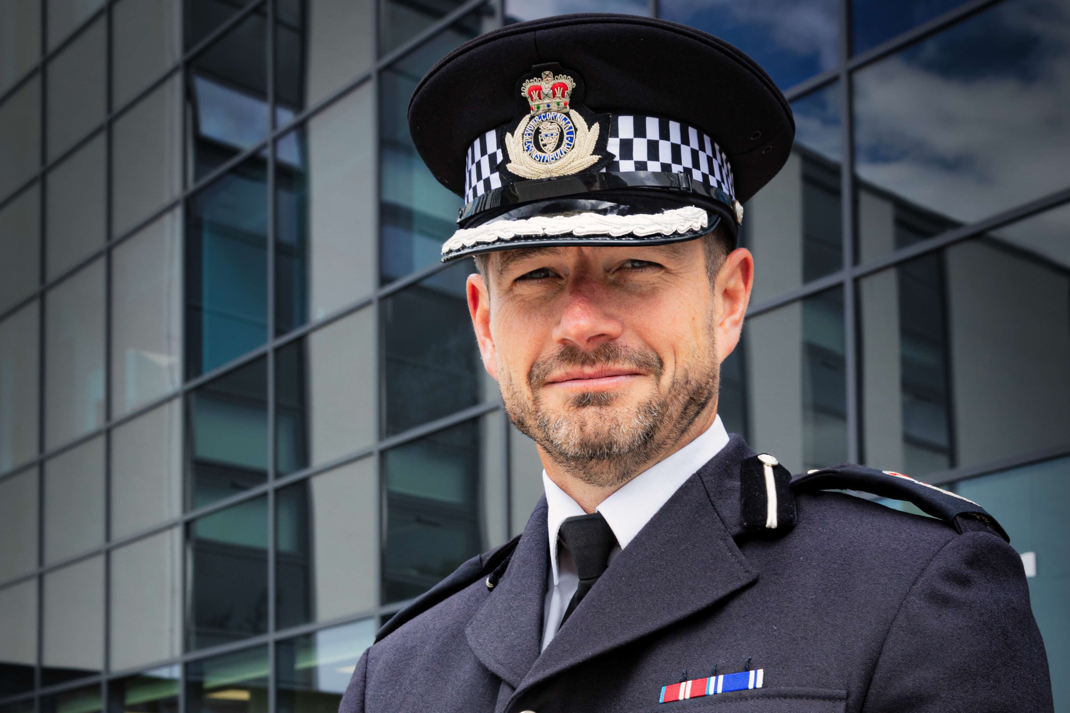 Officer standing looking at a coastal town from a coast path at sunset