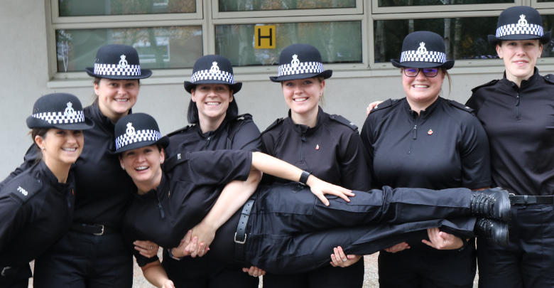 A group of happy police officers holding another officer off the ground