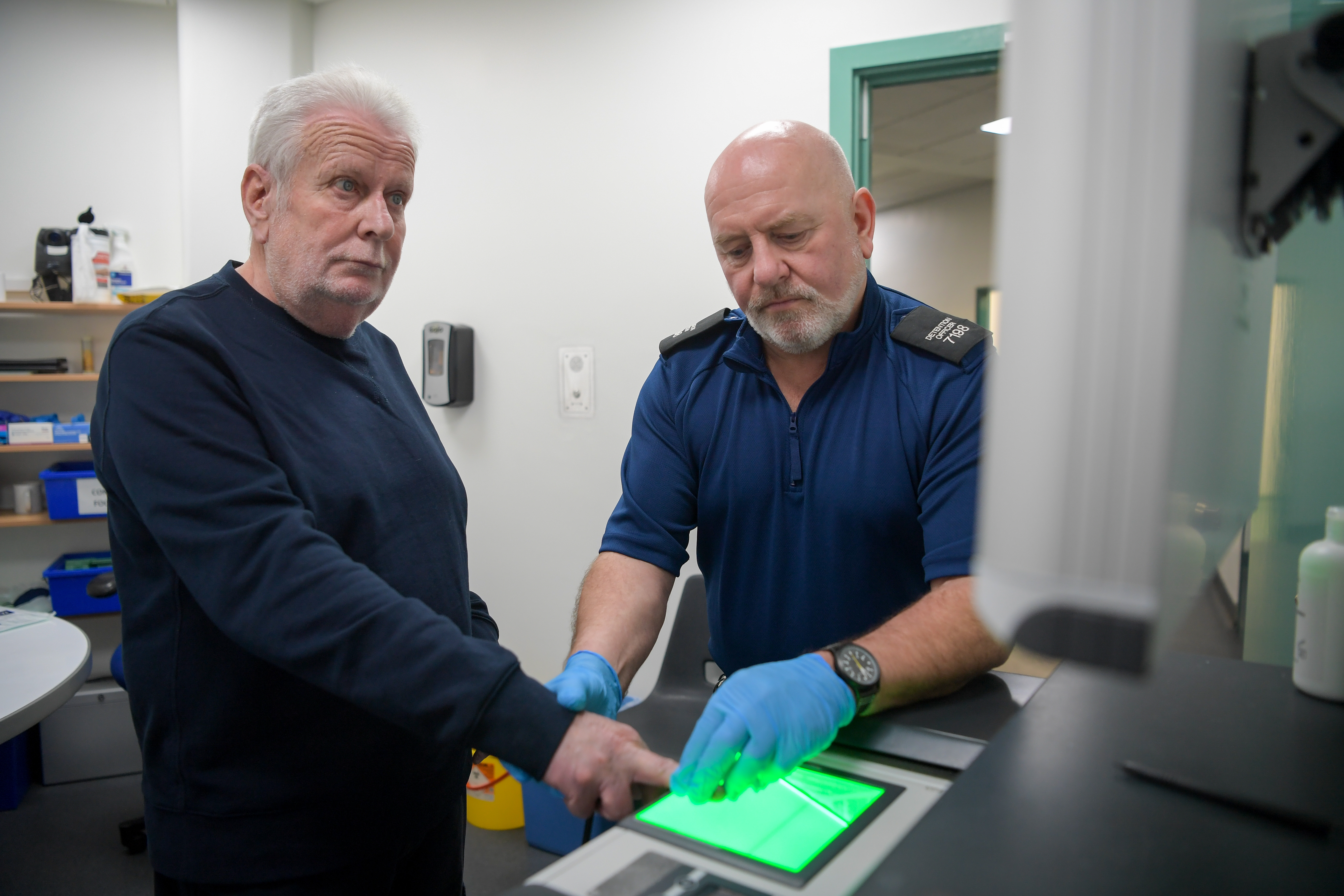 Officer and alleged offender at finger print scanner machine