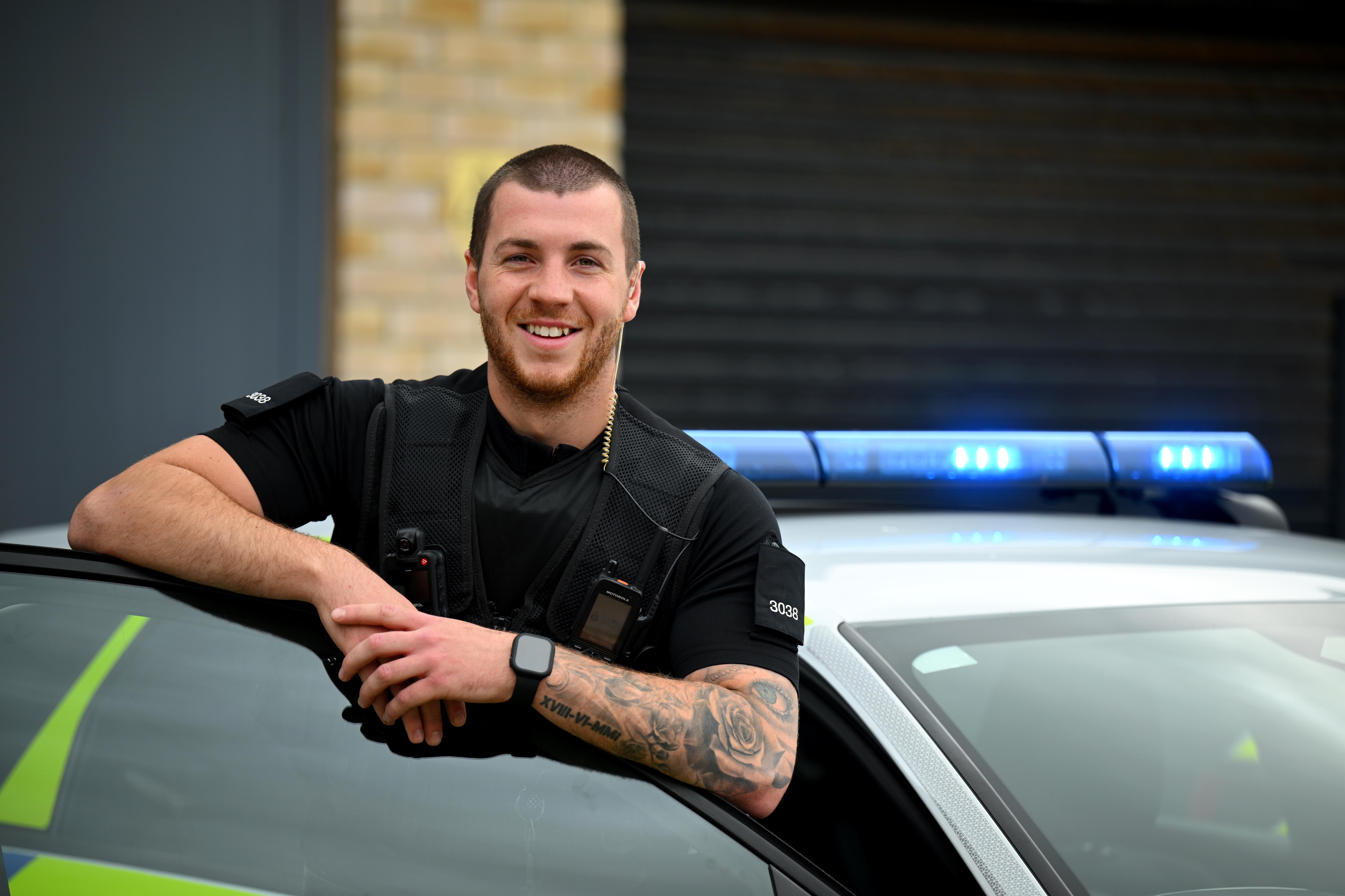 Male Special Constable smiling next to police car