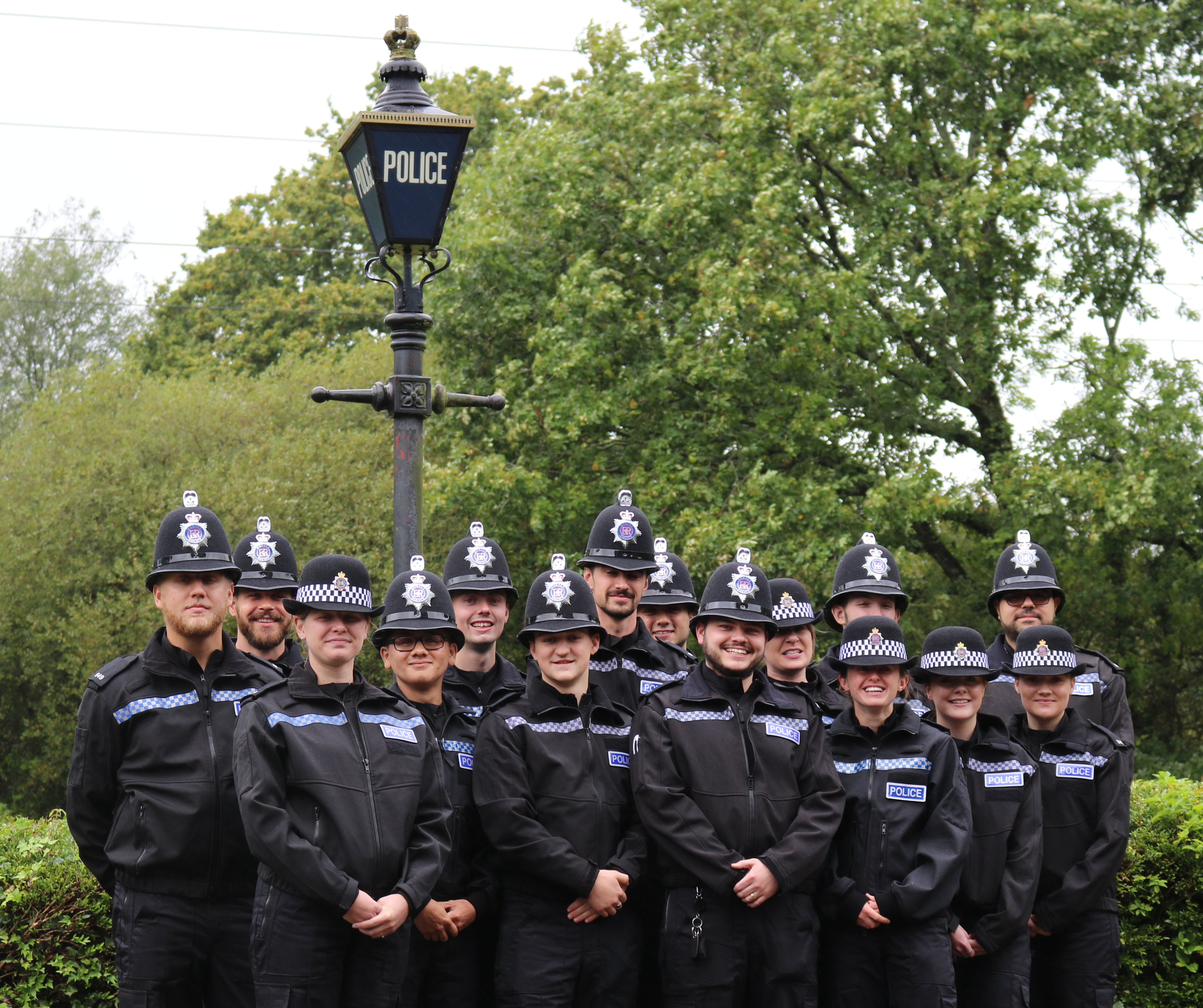 A large group of Police Officers gathered by a police street lamp