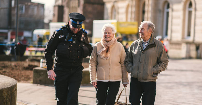 A Police Officer chatting and walking along side an elderly couple