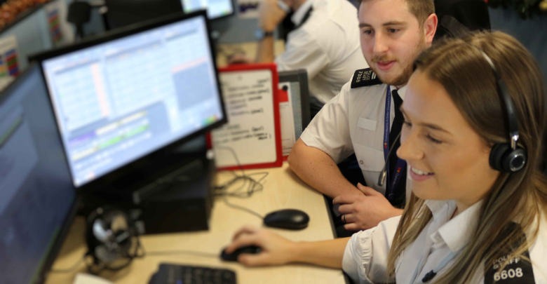 Two call handlers sat at a desk one with a headset on.